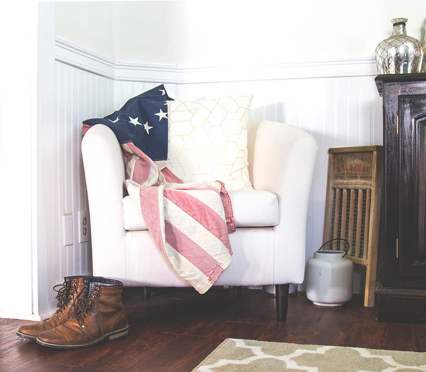 White armchair with American flag throw and brown boots