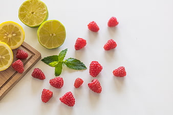 Fresh raspberries, lemons, and mint on white background
