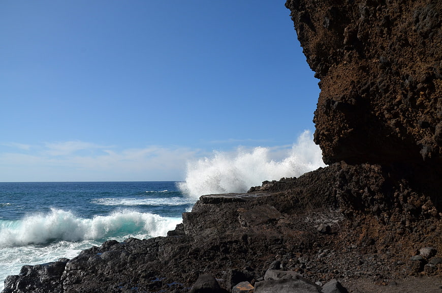 Powerful ocean waves crashing against dark volcanic rocks