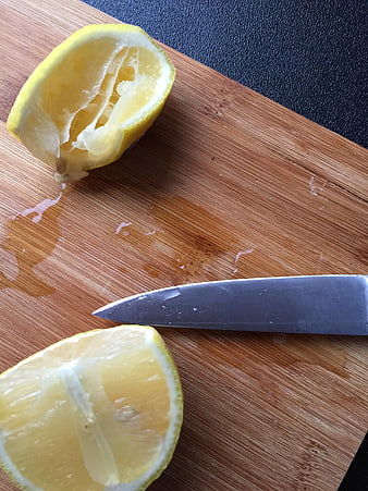 Squeezed lemon halves and knife on wooden cutting board