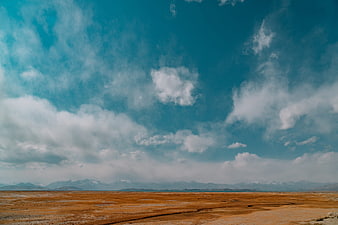 Vast arid landscape with distant snow-capped mountains and blue sky