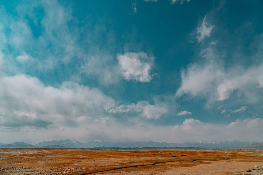 Vast arid landscape with distant snow-capped mountains and blue sky