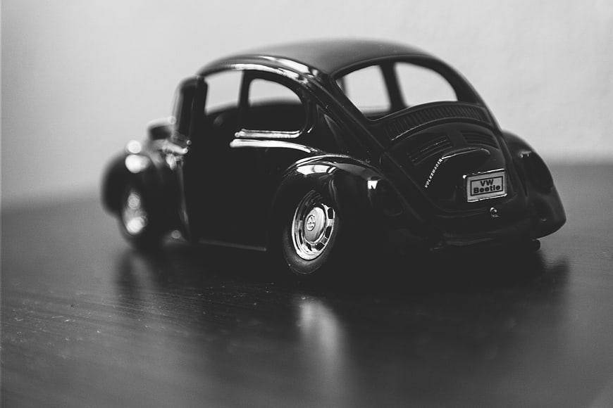 Black and white vintage VW Beetle toy car on dark surface