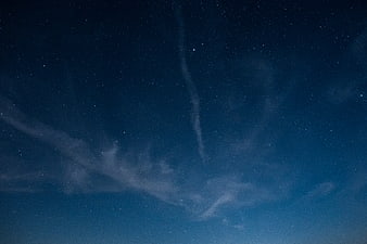 Starry night sky with wispy clouds and deep blue gradient