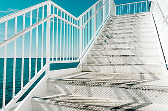 White metal stairs on a boat deck overlooking turquoise ocean