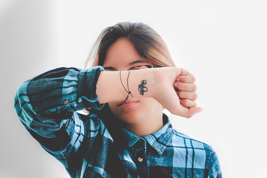 Woman with tattoo on wrist wearing blue plaid shirt