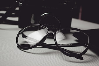Black Eyeglasses on Desk with Vintage Camera Background