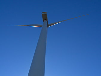 Low angle view of white wind turbine against blue sky