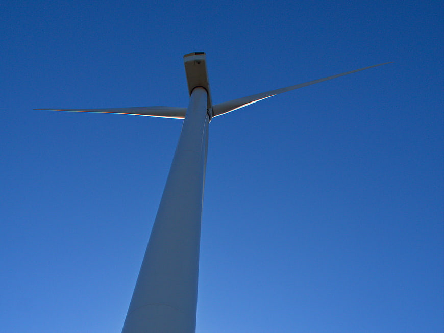 Low angle view of white wind turbine against blue sky