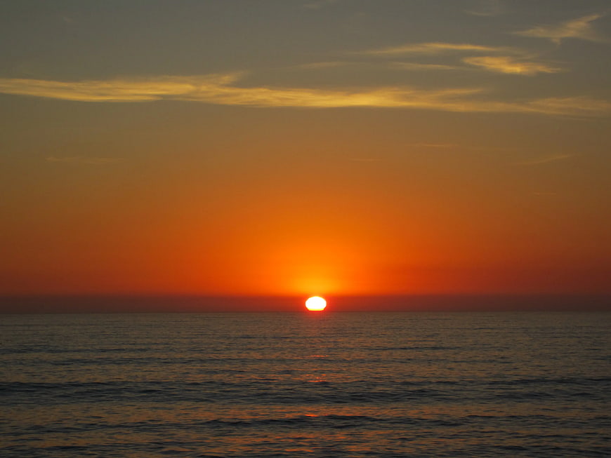 Vibrant Orange Sunset Over Calm Ocean Horizon