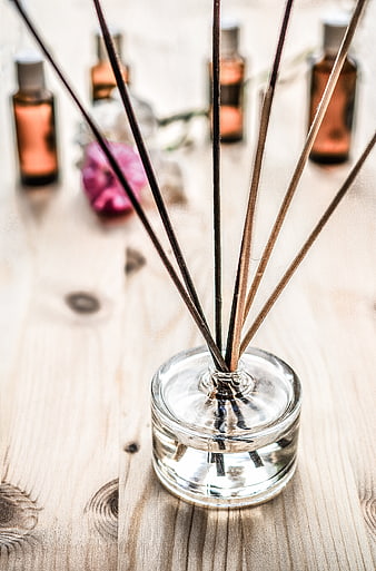 Glass reed diffuser with wooden sticks on light wood table