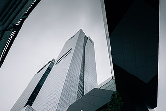 Low angle view of modern glass skyscrapers against gray sky