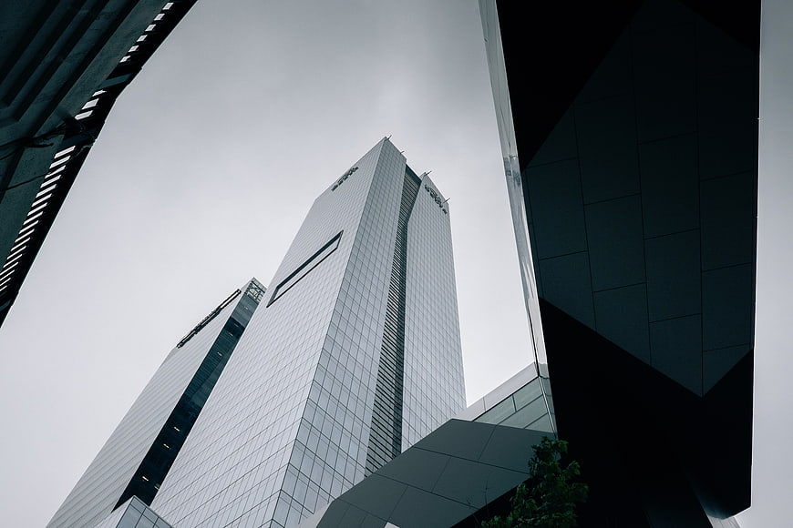 Low angle view of modern glass skyscrapers against gray sky