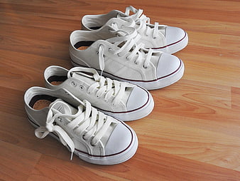 Two Pairs of White Canvas Sneakers on Wooden Floor