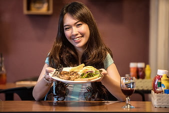 Happy Asian Woman Holding Plate of Food in Restaurant