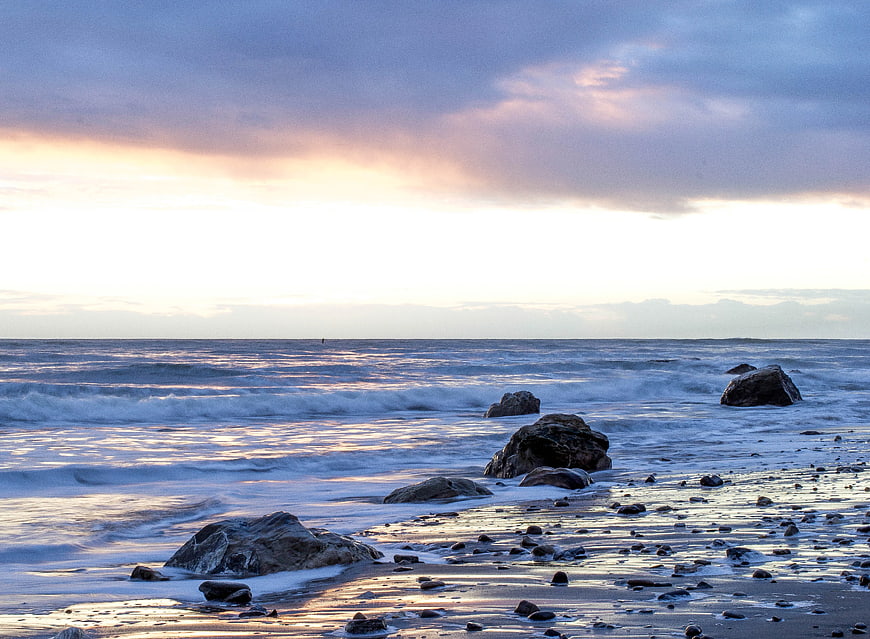Serene Ocean Sunset with Rocks and Gentle Waves