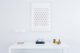 Minimalist white desk with lamp, books, and framed art