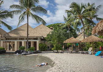 Tropical resort pool with thatched umbrellas and palm trees