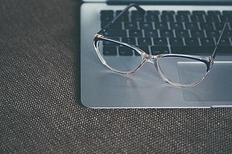 Clear eyeglasses resting on a silver laptop keyboard