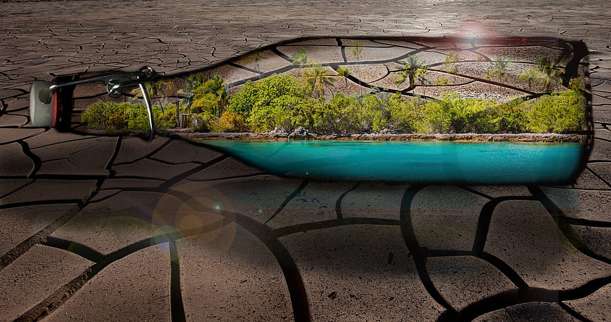 Tropical island landscape inside a glass bottle on cracked dry earth