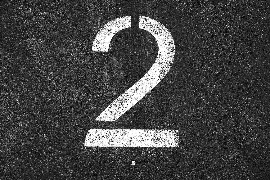 White Number Two Painted On Dark Asphalt Road Surface