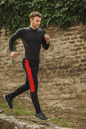 Man jogging outdoors in athletic wear against brick wall