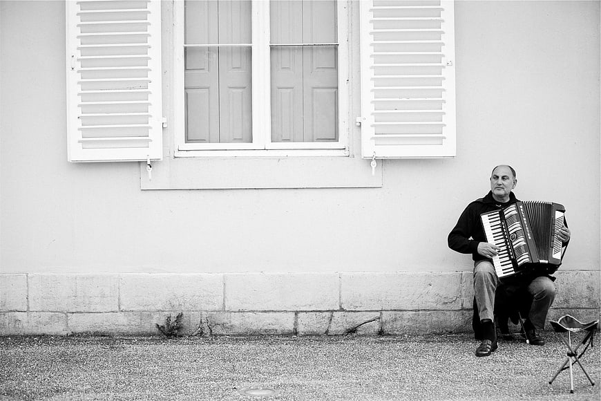 Man playing accordion on street in black and white