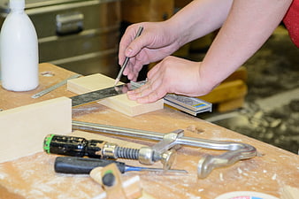 Carpenter marking wood with pencil and ruler on workshop bench