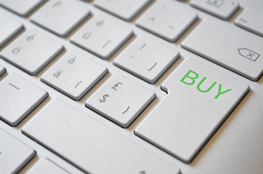 Close-up of a white laptop keyboard with a green BUY button