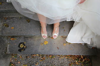 Bride's feet in silver heels on stone steps with autumn leaves