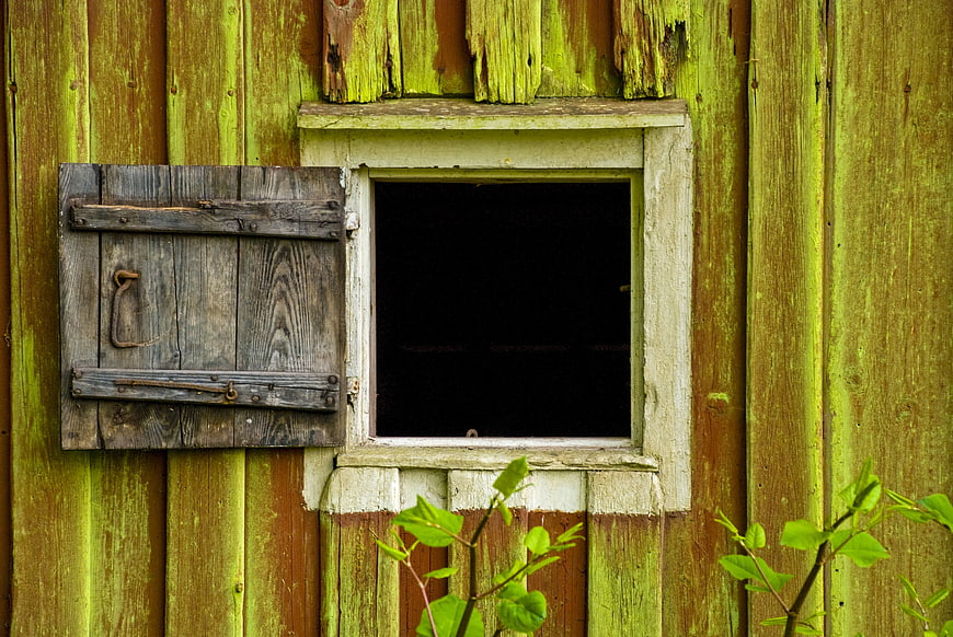 Rustic weathered wooden window with open shutter on old barn