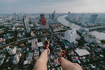 First-person view of legs dangling over Bangkok skyline