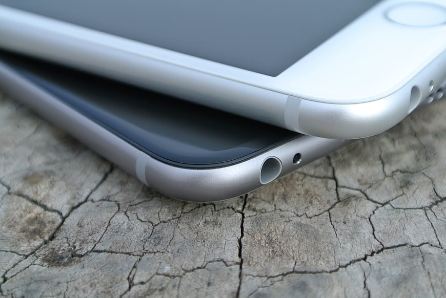 Close-up of two silver smartphones on cracked wood