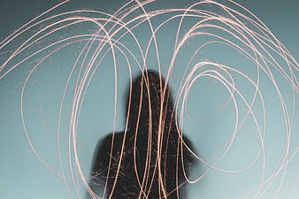 Silhouette of woman with swirling sparks against teal background
