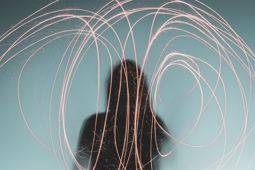 Silhouette of woman with swirling sparks against teal background