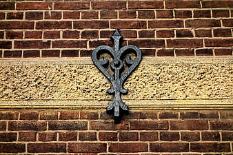 Vintage wrought iron fleur-de-lis on textured brick wall