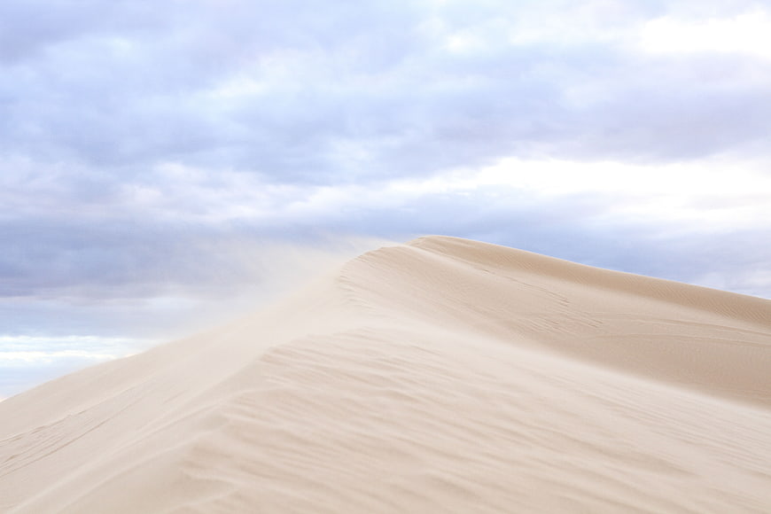 Sweeping Sand Dunes Under Cloudy Sky