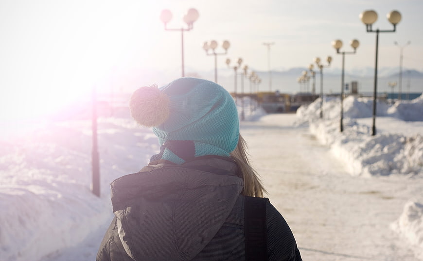 Woman in Blue Beanie Walking on Snowy Winter Path