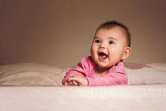 Happy Baby Girl in Pink Outfit Smiling in Crib