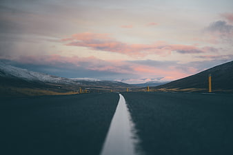 Empty Highway Leading to Snowy Mountains at Sunset