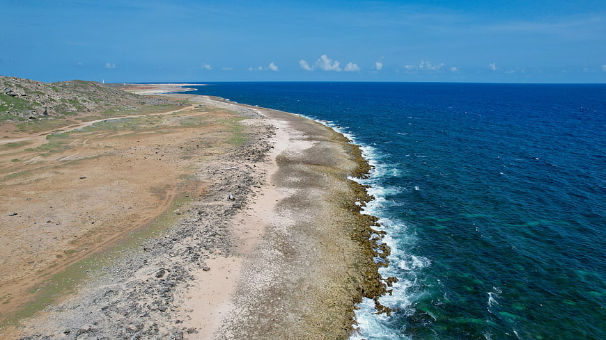 Aerial View of Rocky Coastline Meeting Deep Blue Ocean