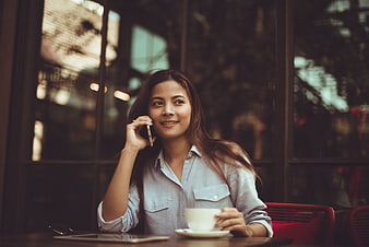 Smiling woman talking on smartphone at cafe table
