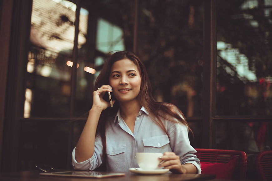 Smiling woman talking on smartphone at cafe table