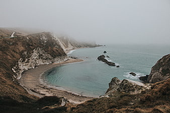 Misty coastal landscape with cliffs and calm ocean bay