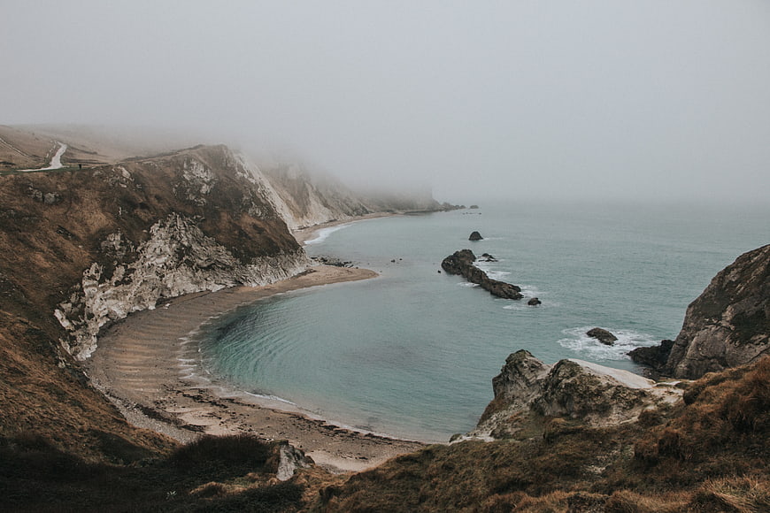 Misty coastal landscape with cliffs and calm ocean bay