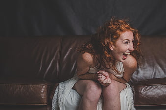 Laughing Redhead Woman Sitting on Brown Leather Sofa