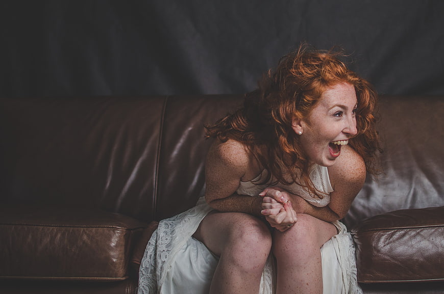 Laughing Redhead Woman Sitting on Brown Leather Sofa