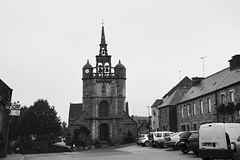Black and white photo of a stone church bell tower in a European town square