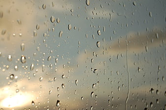 Raindrops on Glass Window with Soft Sunset Background
