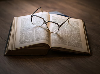 Vintage eyeglasses resting on an open book on a wooden table